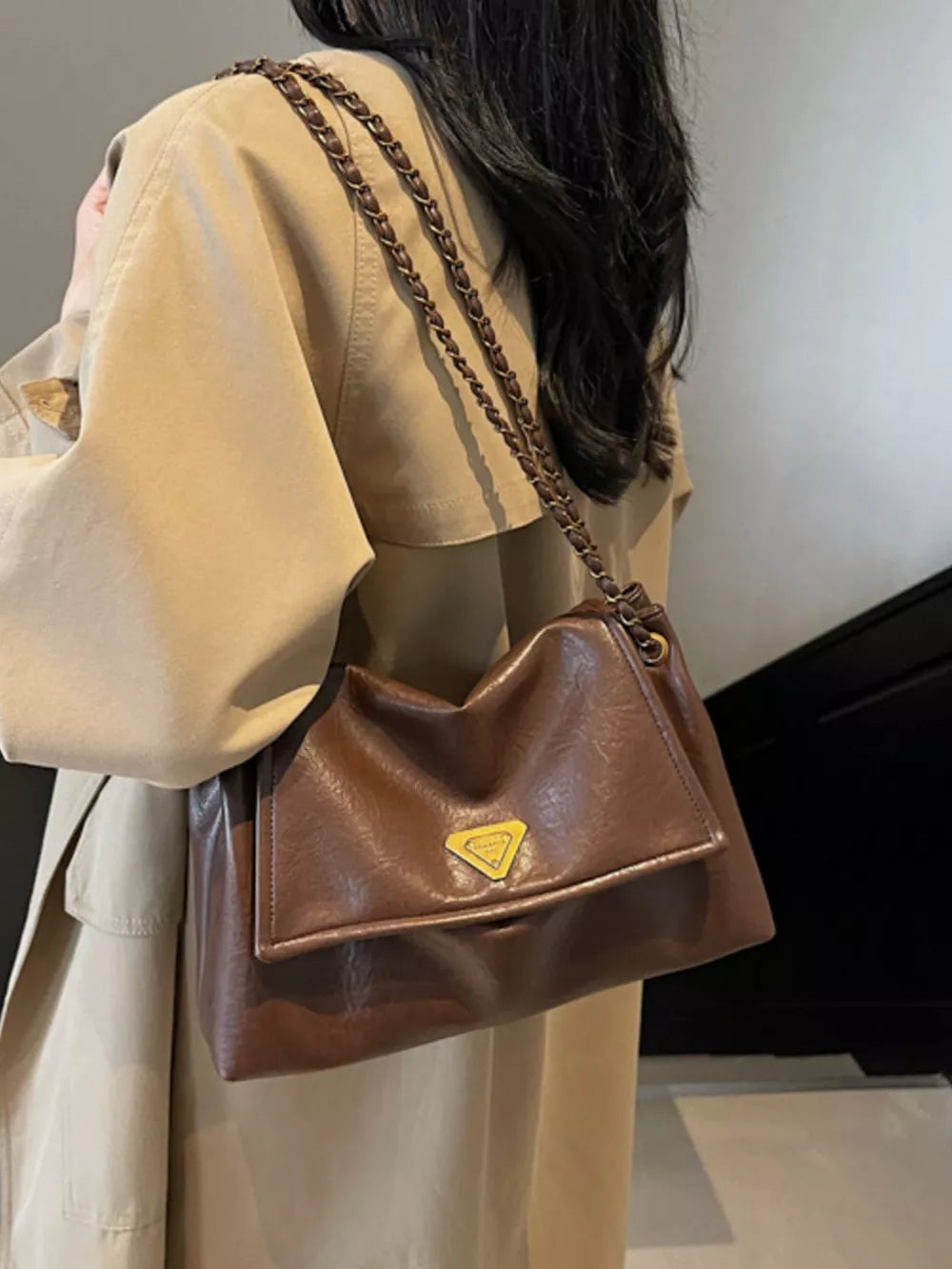 Brown flap shoulder bag with chain detail and gold triangle logo