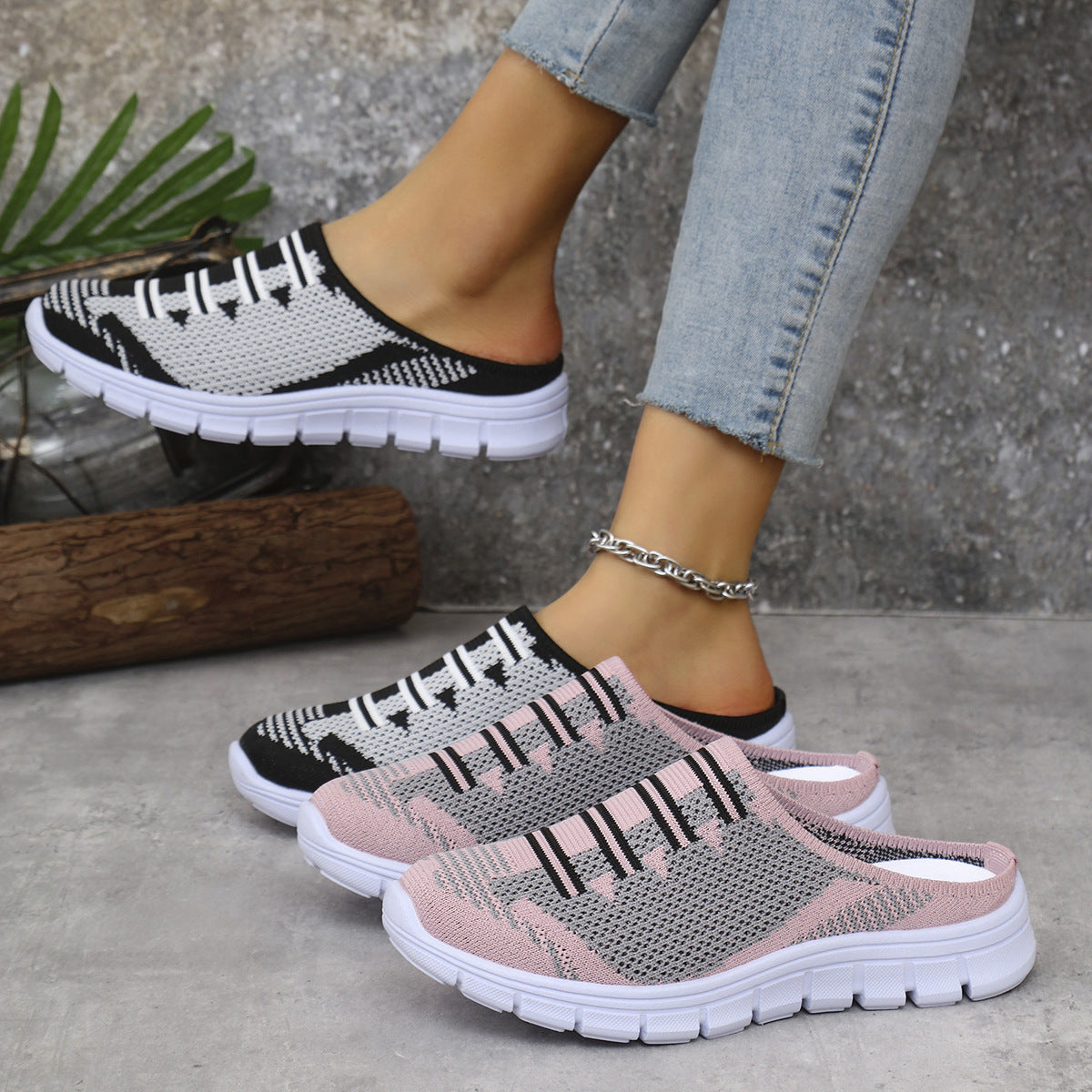 Pink and black knit slip-on sneakers with white soles and decorative laces.