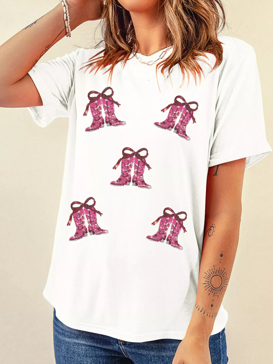 White t-shirt with a graphic print of pink sequined cowgirl boots with bows.