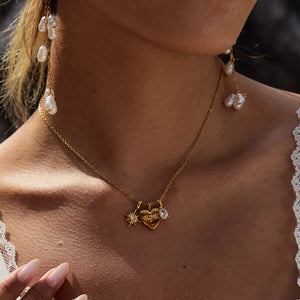 Gold heart charm necklace with MOM engraving and celestial details.