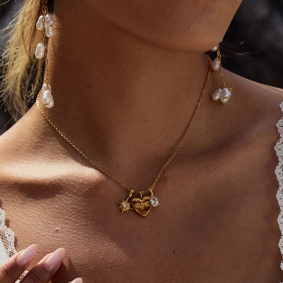 Gold heart charm necklace with MOM engraving and celestial details.