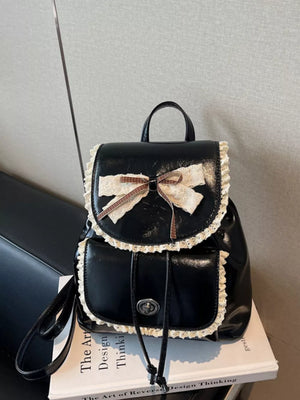 Black mini backpack with lace trim, bow, and plaid ribbon detail.