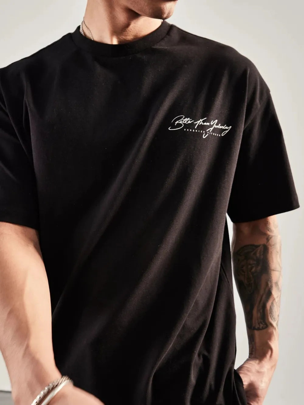 Black oversized graphic tee with white script print on chest and back print detail.