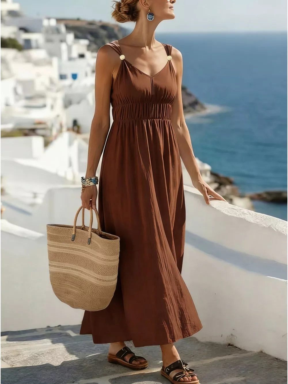 Brown V-neck sleeveless maxi dress with ruched waist and gold-tone shoulder details.