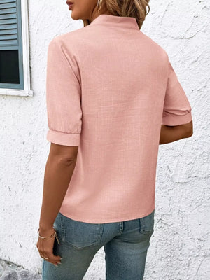 Pink embroidered notched blouse with cuffed sleeves and a high neckline.