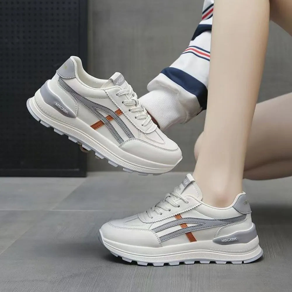 White platform sneakers with gray and orange contrast stripes and a thick sole.