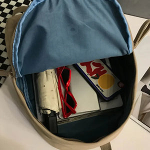 Khaki canvas backpack open showing interior with sunglasses, umbrella, and phone case.