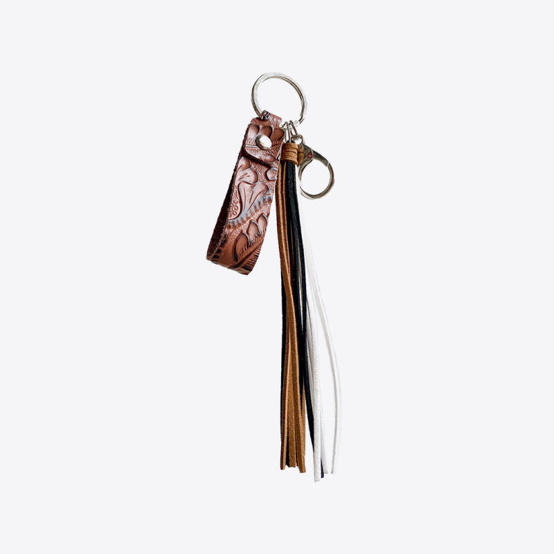 Textured leather keyring with embossed pattern and multiple leather tassels in brown, black, and white.