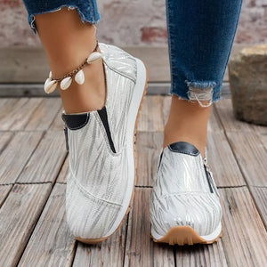 White zebra print slip-on flats with side zippers and black accents.