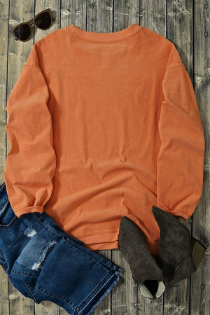 Orange corduroy sweatshirt with ribbed texture and crew neck, styled with jeans and boots.