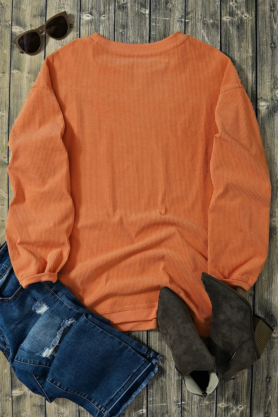 Orange corduroy sweatshirt with ribbed texture and crew neck, styled with jeans and boots.