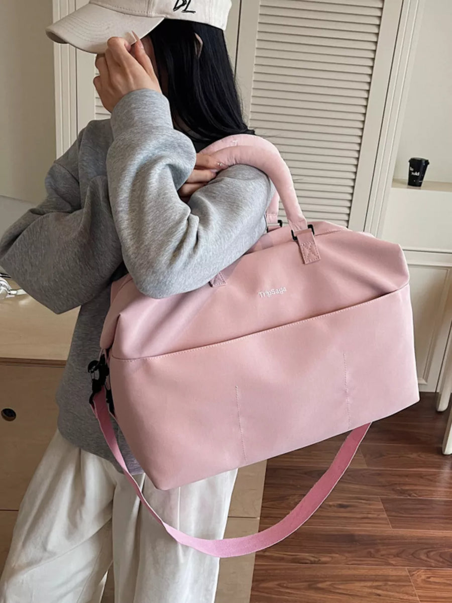 Pink duffel bag with top handles and adjustable strap, featuring a front pocket and embroidered logo.