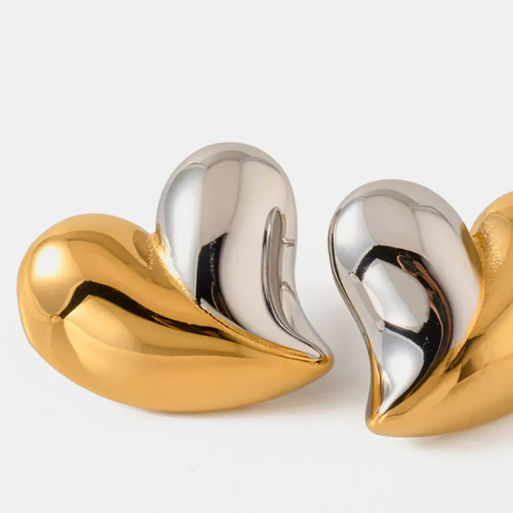 Two-tone heart sculptural stud earrings in gold and silver.