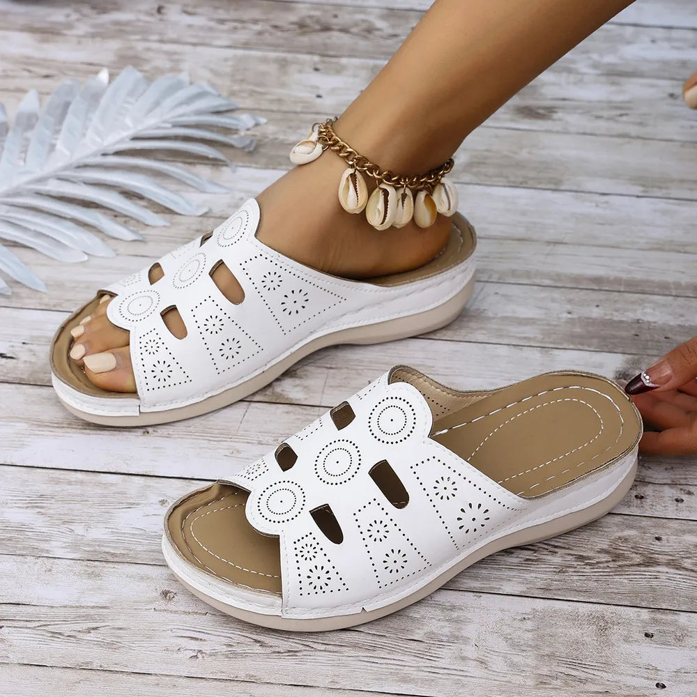 White laser-cut comfort slide sandals with open toe and patterned cutouts.