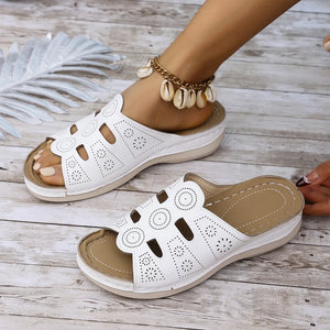White laser-cut comfort slide sandals with open toe and patterned cutouts.