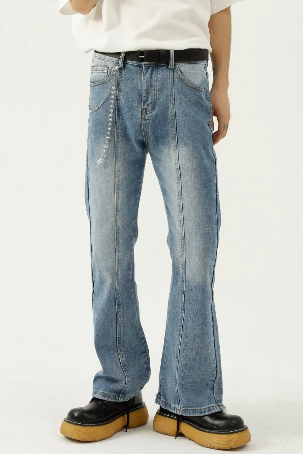 Medium wash denim flare jeans with prominent seam details and a chain accessory.