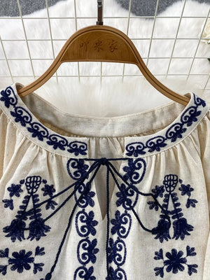 Cream tie-neck blouse with intricate navy embroidery and tassel ties