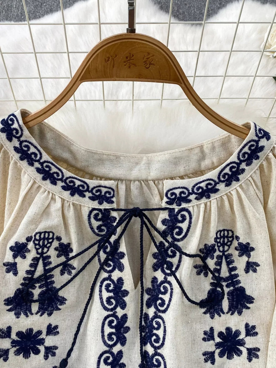 Cream tie-neck blouse with intricate navy embroidery and tassel ties
