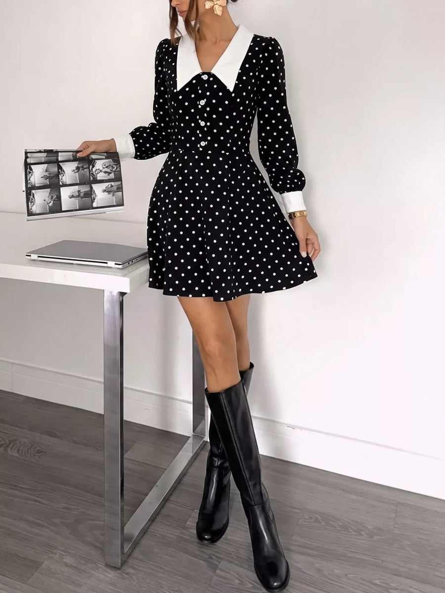 Black polka dot dress with white collar and cuffs, button front, long sleeves, and flared skirt.