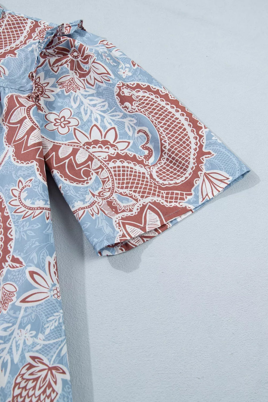 Cotton button-up shirt with blue floral paisley print and scalloped trim detail.