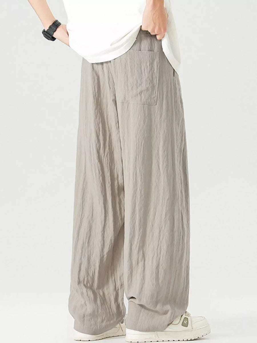 Lightweight wide-leg trousers in light gray with a drawstring waist and pocket detail.
