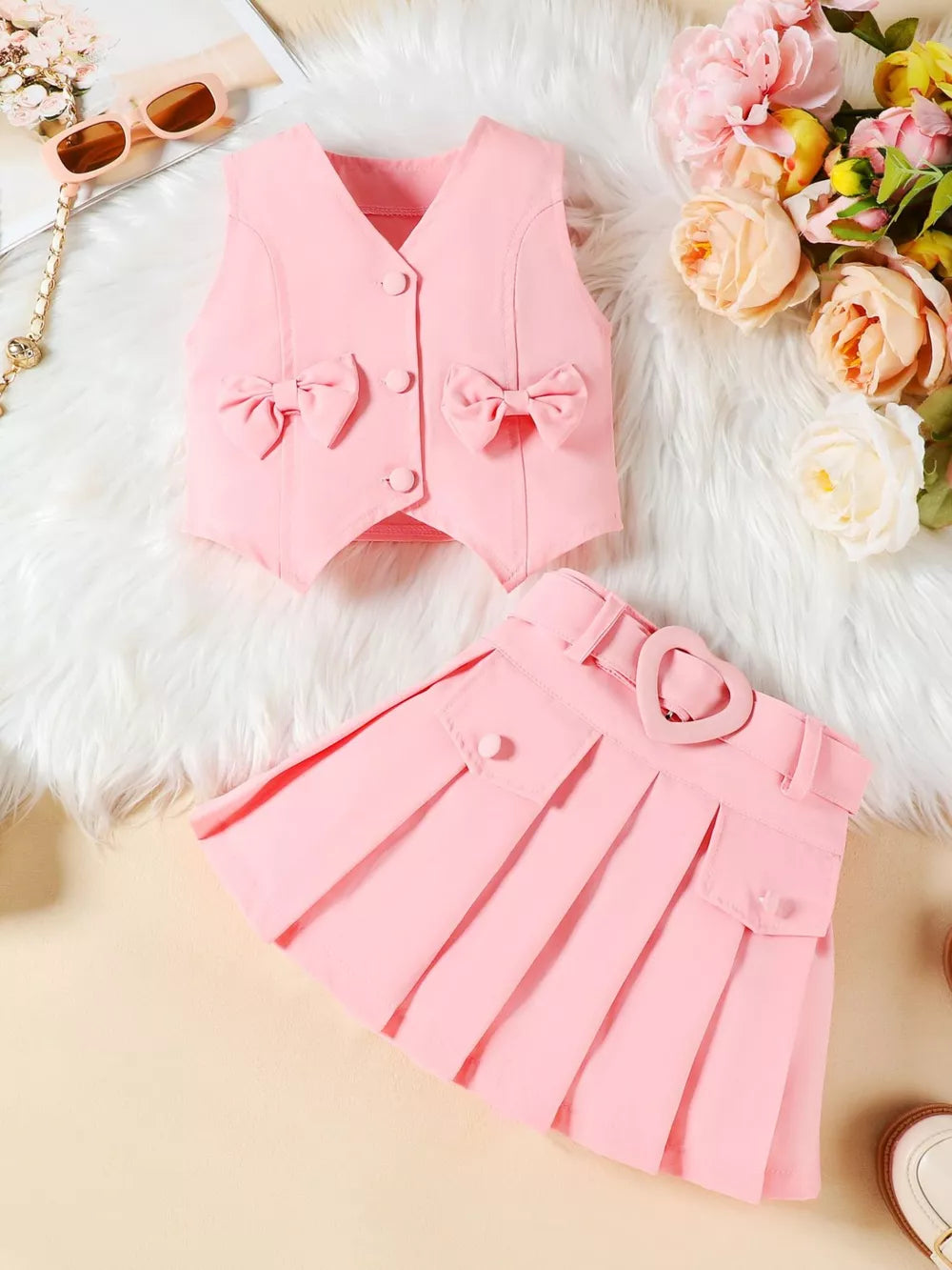 Pink baby vest with bowknot details and pleated skirt with heart buckle.