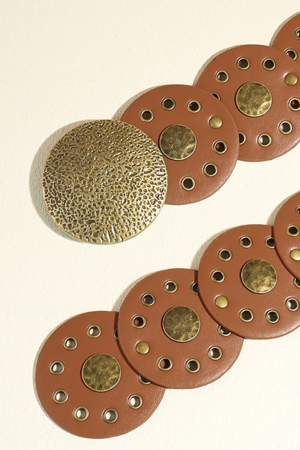 Brown faux leather belt with round disc embellishments and metal eyelets.