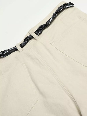 Cream white maternity pants with a black patterned braided belt and wide-leg cut.