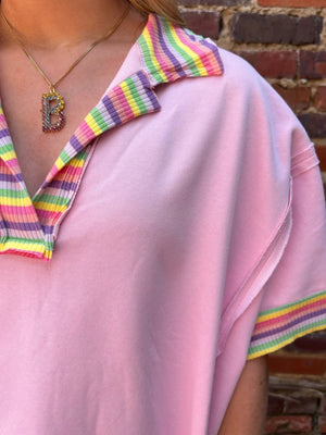 Pink cotton V-neck top with rainbow striped collar and cuffs, exposed seams