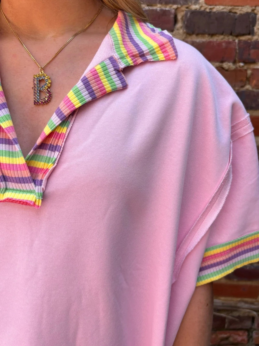 Pink cotton V-neck top with rainbow striped collar and cuffs, exposed seams