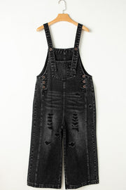 Black distressed denim culotte overalls with button closures and wide legs.