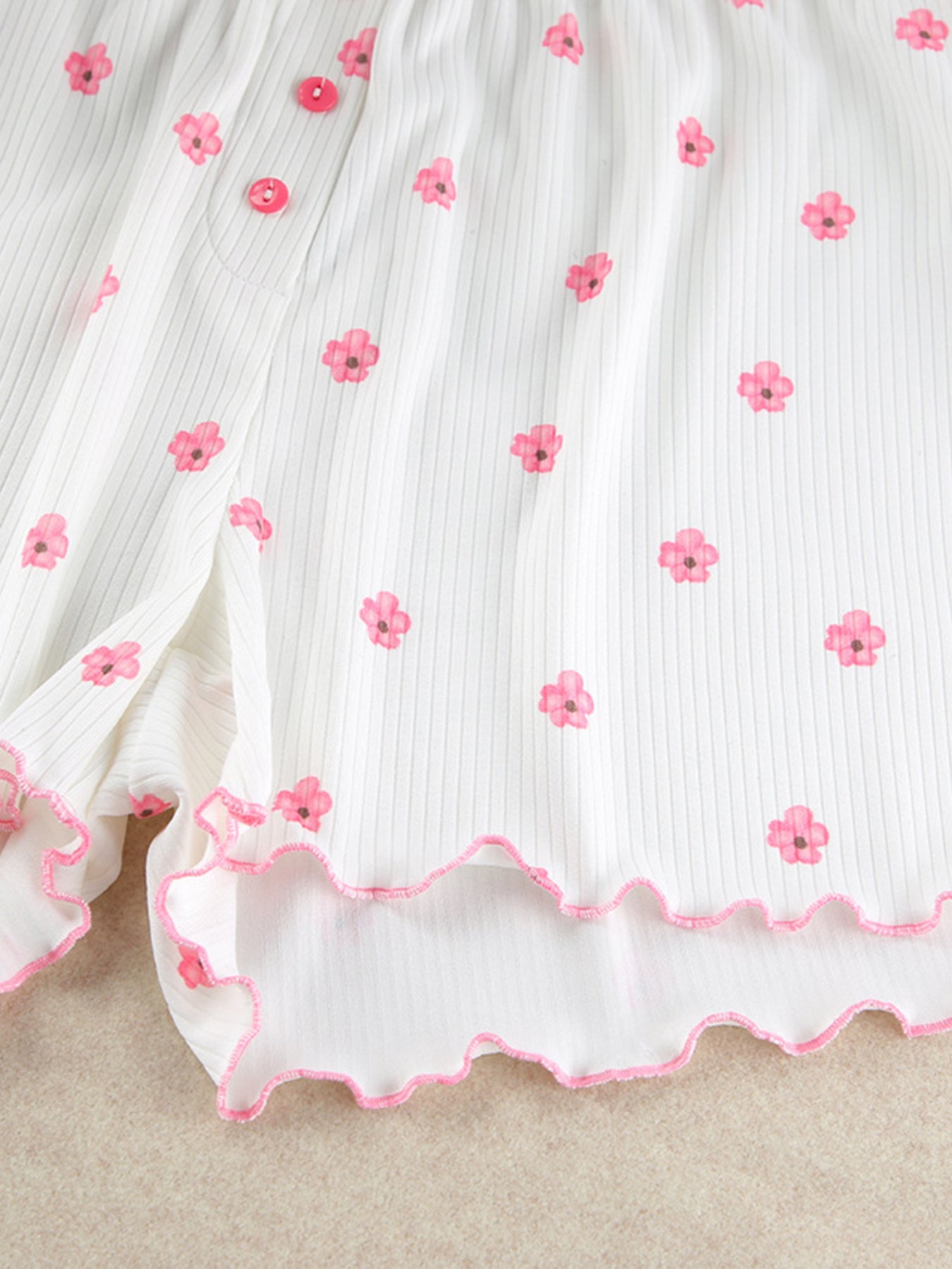 White ribbed knit shorts with pink floral print and frill trim.