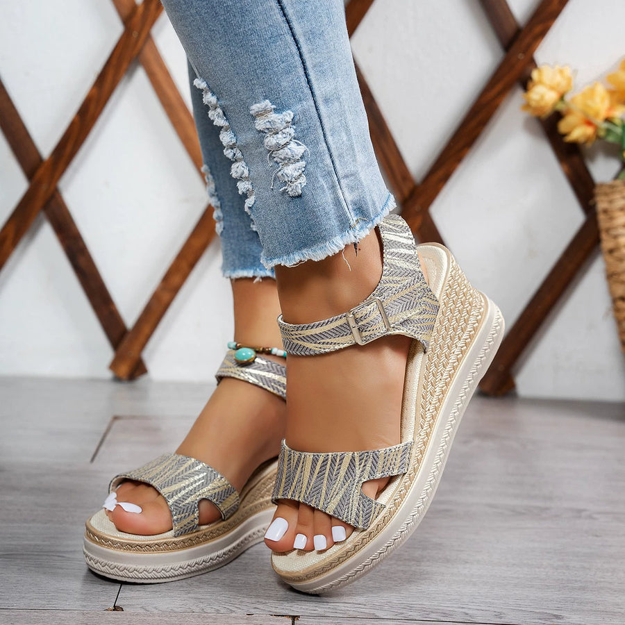 Elegant open-toe wedge sandals in brown with adjustable strap and patterned detail.