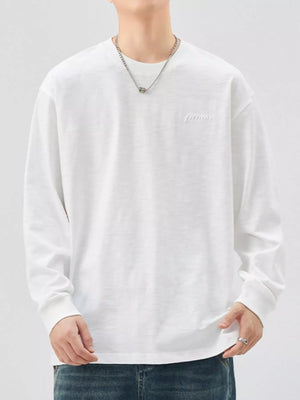 Oversized white cotton long-sleeve tee with subtle embroidered logo detail.