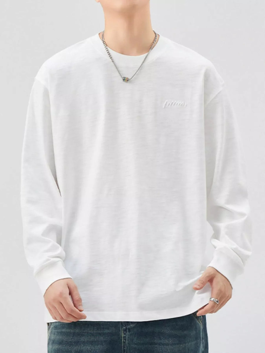 Oversized white cotton long-sleeve tee with subtle embroidered logo detail.