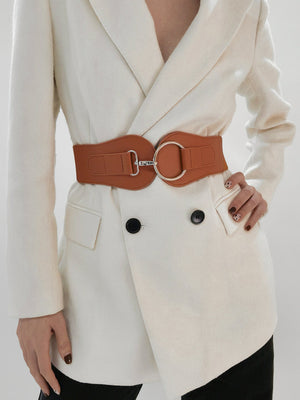 Caramel wide belt with sculpted silver buckle cinching a cream blazer.