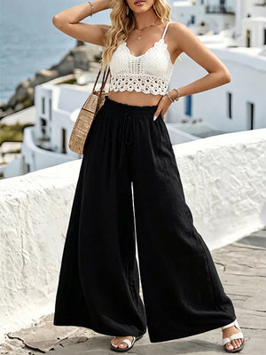 Black wide-leg linen pants with drawstring waist and a white crochet crop top.