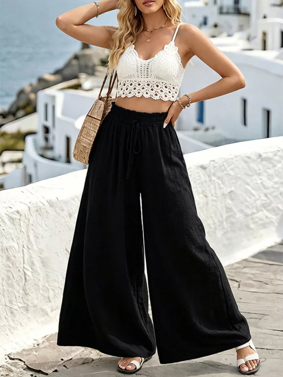 Black wide-leg linen pants with drawstring waist and a white crochet crop top.