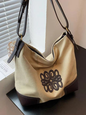 Khaki canvas tote bag with dark brown leather trim and embroidered logo
