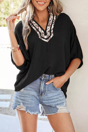 Black polyester tunic with leopard print notched neckline and cuffed sleeves.