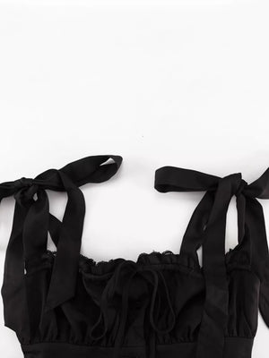 Black satin cami with tie straps, lace trim, and a ruched neckline.
