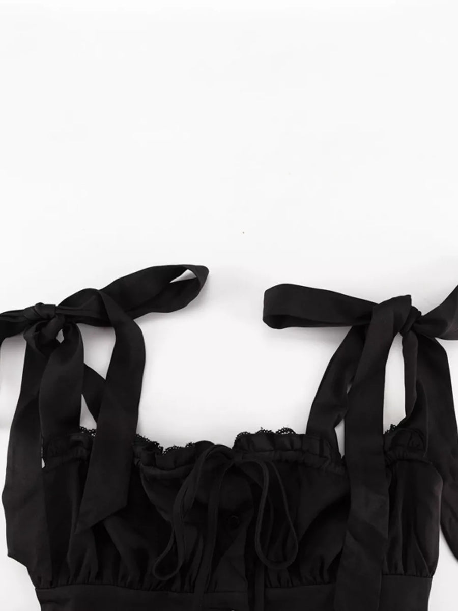 Black satin cami with tie straps, lace trim, and a ruched neckline.