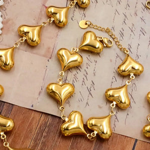 Gold bracelet featuring heart charms and geometric
