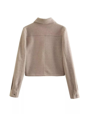 Beige trucker jacket with collared neckline, long sleeves, and button cuffs.