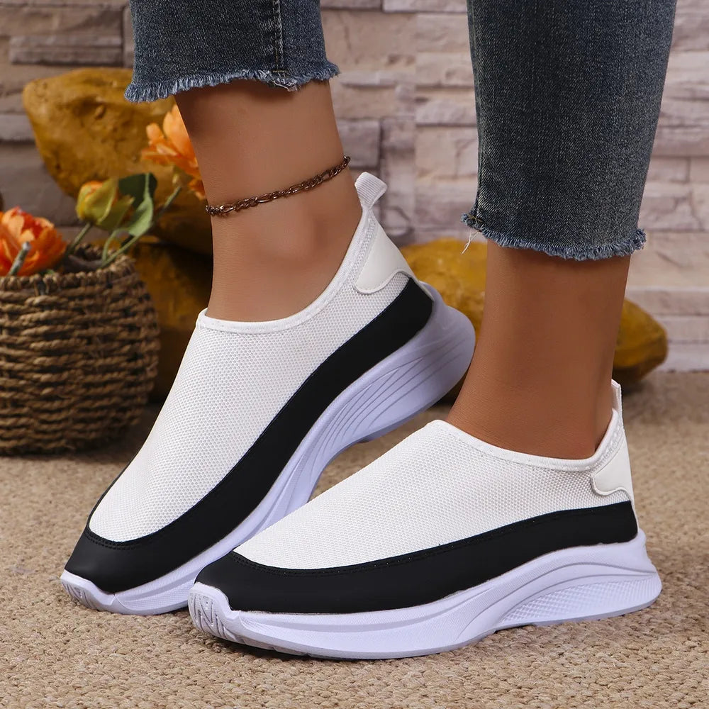 White mesh slip-on sneakers with black stripe detail and white soles.