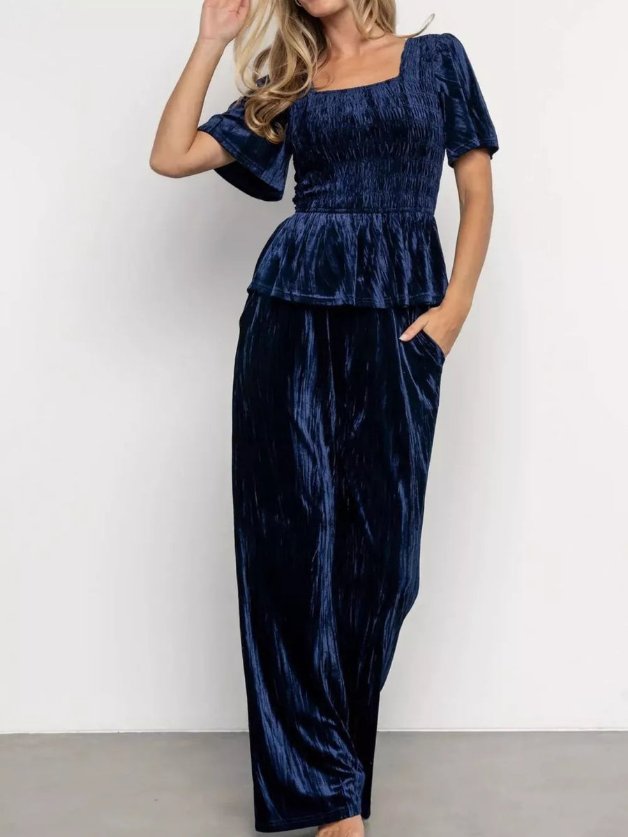 Navy blue velvet two-piece set with smocked bodice, peplum, flutter sleeves, and wide-leg pants.