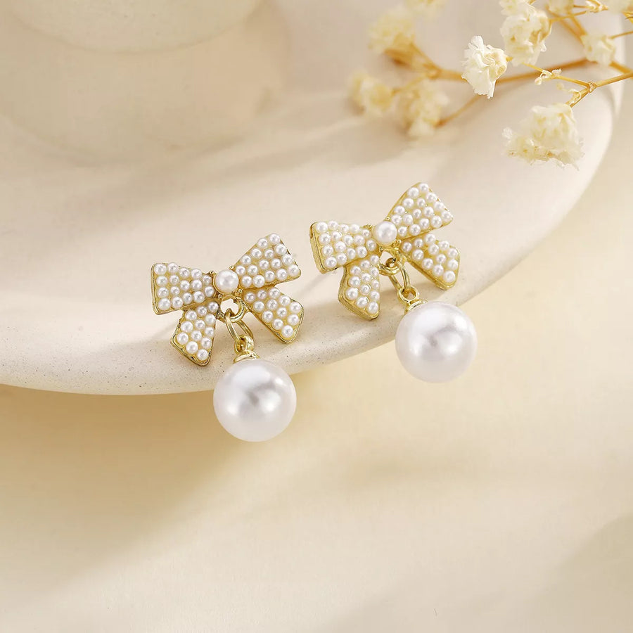 Gold bowknot pearl drop earrings with 18K gold plating and pearl accents.