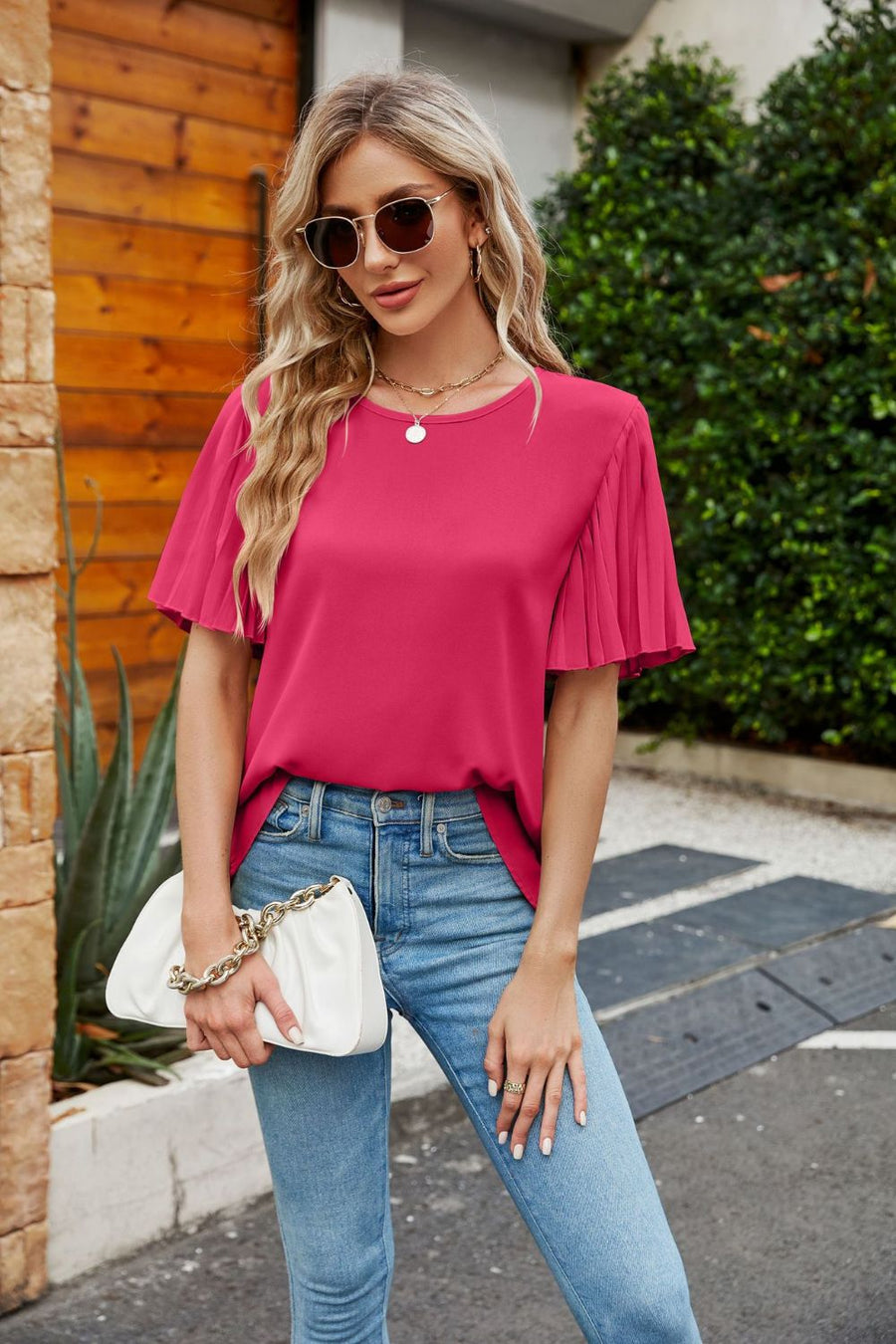 Deep Rose blouse with pleated short sleeves and crew neck, styled with jeans and a white clutch.