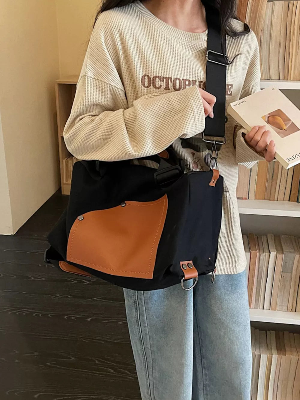 Black nylon crossbody bag with tan contrast pocket and adjustable strap.