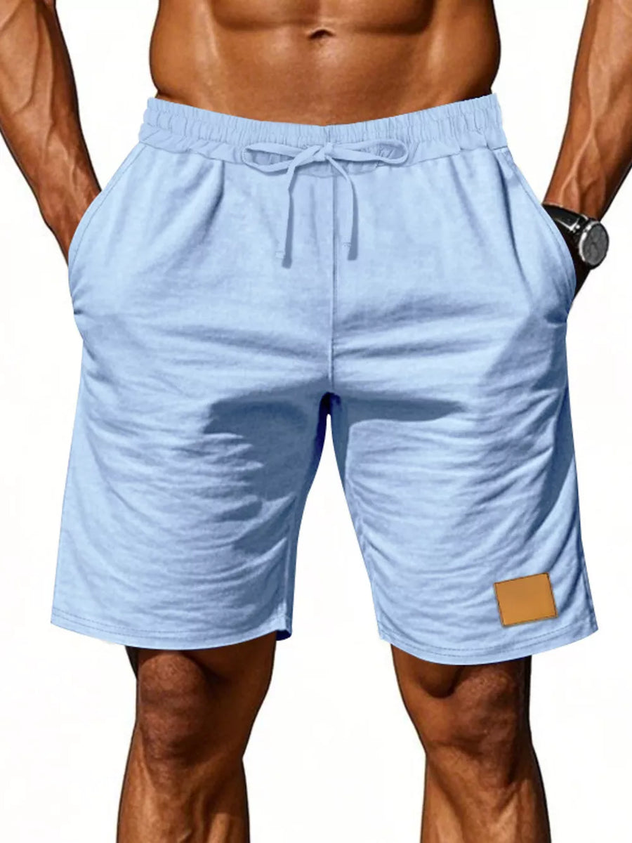 Light blue chino shorts with drawstring waist and leather patch detail.